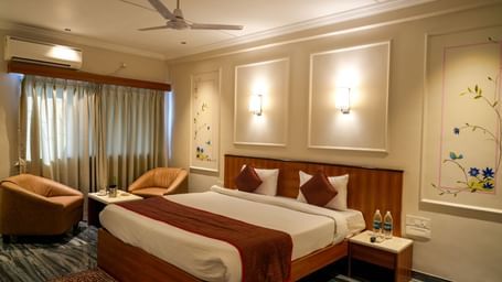 Stylish guest room with a double bed, seating area, and soft lighting at Pravasa Hotel Kolhapur.