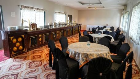 Banquet hall with round tables and elegant seating for gatherings at Pravasa Hotel Kolhapur.