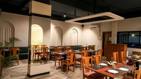 Modern restaurant with chic decor and wooden furnishings at Pravasa Hotel Kolhapur.