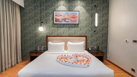 A room with a king size bed, featuring a heart made of rose petals on the duvet at Pushkara Resort & Spa.