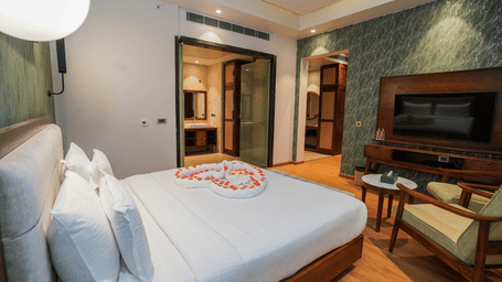A room with a flower-adorned bed, TV, and a view into the bathroom at Pushkara Resort & Spa.