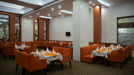 A comfortable hotel dining area with a round wooden table, chairs, and sofa seating - Ramada by Wyndham Bodh Gaya Mahabodhi