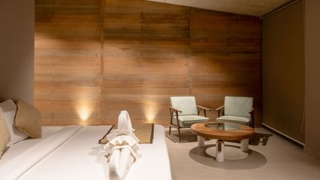 A spacious living area with textured wooden walls, a seating arrangement, and a rug on the floor | Gaia Room | RD's Nature Retreat, Bangalore