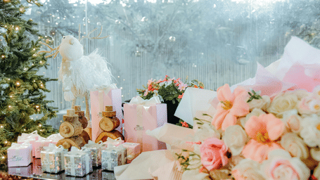 A table filled with flowers and gift boxes in an indoor setup.
