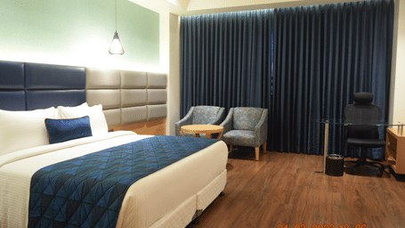 A comfy premium room with king size bed , chair at SRM Hotel Maram Malai Nagar, Chennai