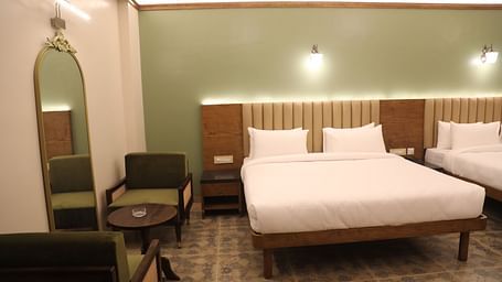 two double beds, a seating area and a mirror in one of the Heritage Suites at Summer House, Nandi Hills