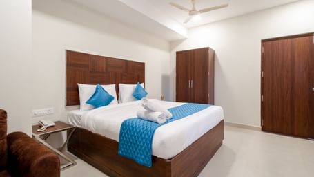 Neatly arranged bedroom featuring double bed blue decor soft lighting and wooden furniture creating a cosy stay at Swarna's The Capital.