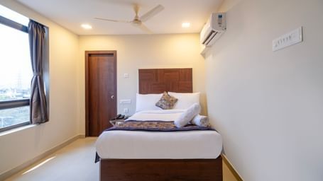Bright bedroom with double bed soft furnishings ceiling fan air-conditioning and window for natural light at Swarna's The Capital.