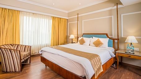 Spacious bed and a large window covered by curtains.