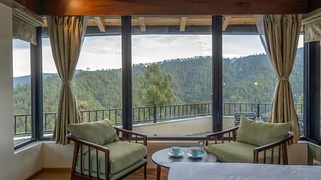 Spacious room with a seating area featuring armchairs and a view through large windows at The Chamomile Estate.