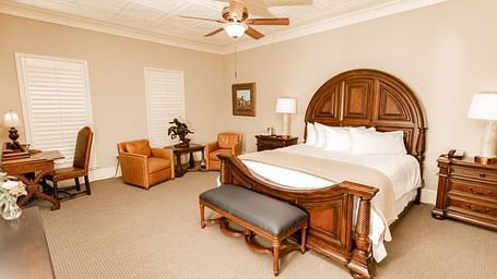 Bedroom with wooden bed and leather seating at The Grand Hotel & Ballroom, McKinney.