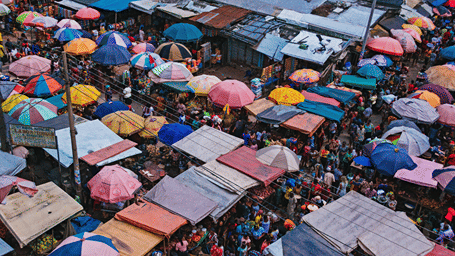 An aerial view of a vibrant, tightly packed market filled with colorful parasols and stalls.