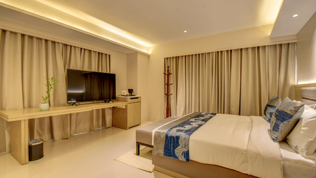 A hotel room with a bed, a television, and a desk, natural light coming through the window - The SSK Solitaire Boutique Hotel & Spa, Gangapur Road - Nashik