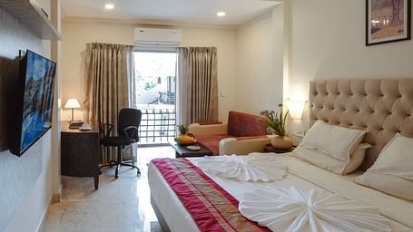 A spacious bedroom featuring a bed, a large TV, and a balcony with natural light – The Verda de Miranda Resort.