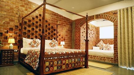A bedroom with a bay window bed and a lamp beside it at Tisya Farms, Gurgaon.