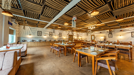 Himalayan Spices restaurant at Vedikant Resorts The Mallard Corbett featuring several sets of chairs and tables, sofas, and food counters for the buffet.