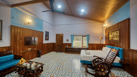 The interior of a room with a patterned floor, and wooden ceilings, featuring a sofa, a rocking chair, and a decorative coffee table. - Vintage Trails by Ilara