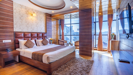 Room interior with bed, rug, and window seating at Yashshree Jai Hotel & Banquet, Darjeeling.