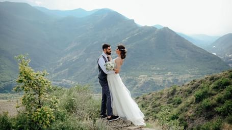 a couple posing for a photograph in western wedding attire in the moutains