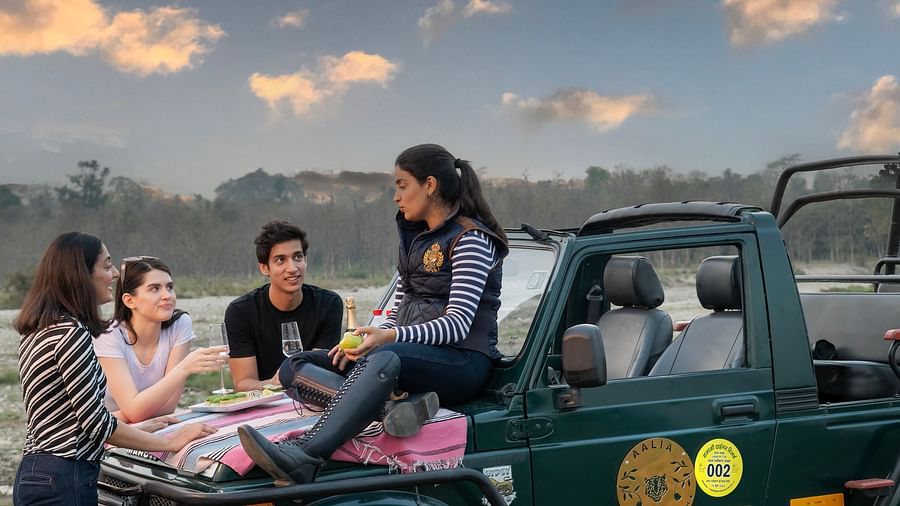 A group of friends enjoying a picnic with one of the friends sitting on top of a jeep - Aalia Jungle Resort & Spa