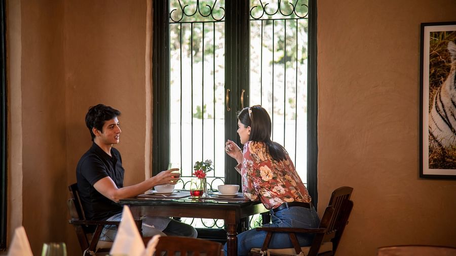 A couple enjoying a breakfast by the window at our restaurant near Haridwar - Aalia Jungle Resort & Spa