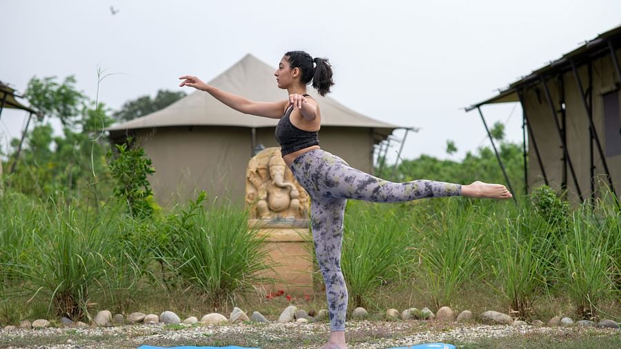 A woman striking a yoga posing in front of one of our tents in Haridwar - Aalia Jungle Resort & Spa
