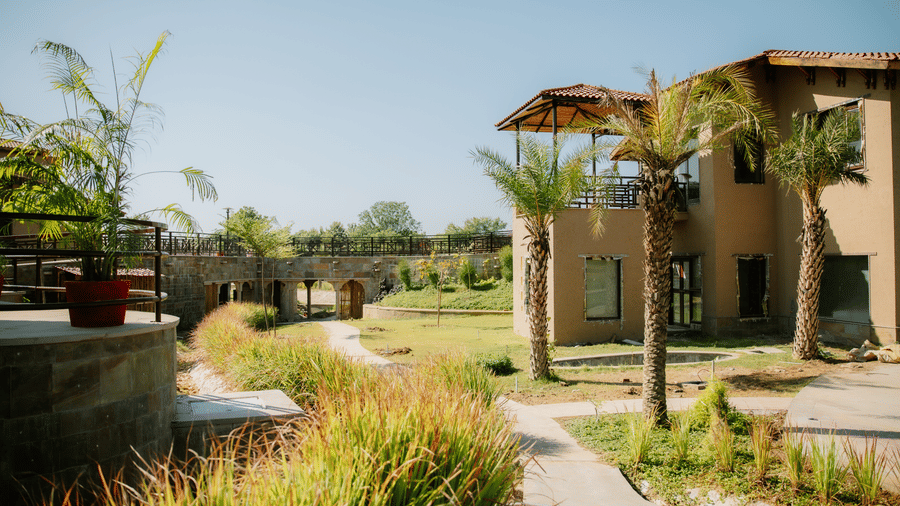 A scenic pathway leading to a resort building amidst green landscaping at Aamaghati Wildlife Resort.