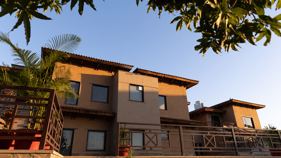 The modern yet traditional resort buildings viewed from a lower angle, under a tree, at Aamaghati Wildlife Resort.