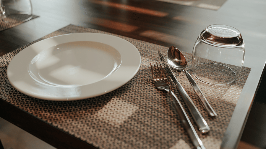 A close-up of a perfectly set dining table with a plate and cutlery at Aamaghati Wildlife Resort.