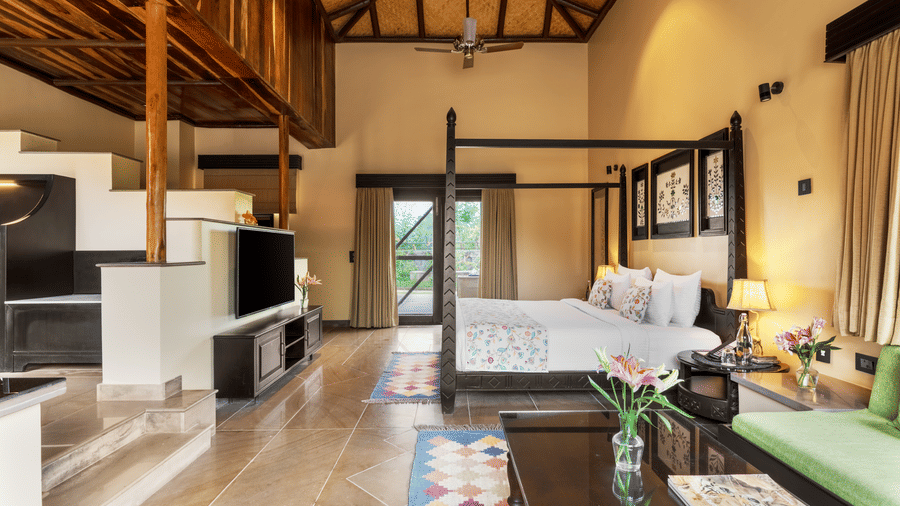 An overview of a well-designed suite featuring a bed and living area at Aamaghati Wildlife Resort.