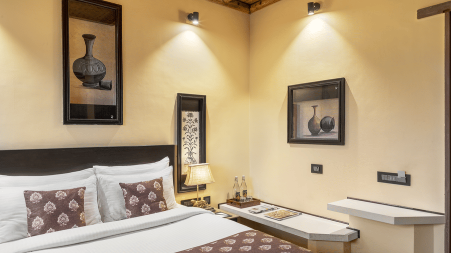 A serene bedroom with a large bed, and matching lamps on either side at Aamaghati Wildlife Resort.