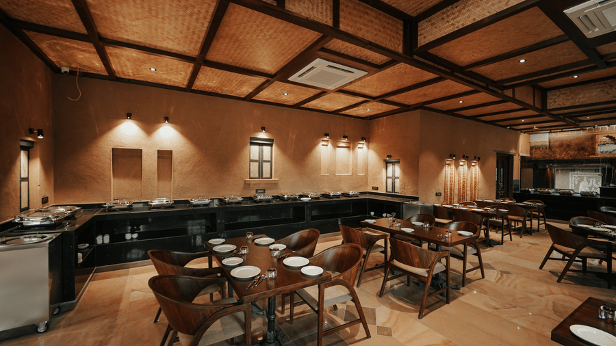 A restaurant dining area with a buffet counter and set tables at Aamaghati Wildlife Resort.