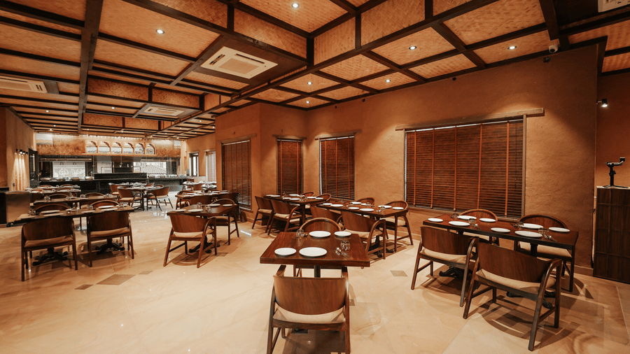 The expansive restaurant interior showcasing its unique ceiling design and tables at Aamaghati Wildlife Resort.