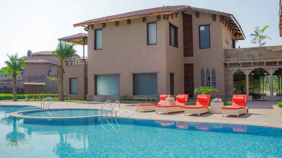  A resort building overlooking a large, inviting swimming pool with sunbeds at Aamaghati Wildlife Resort.