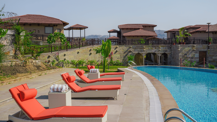 The resort swimming pool with loungers, overlooking a beautiful landscape at Aamaghati Wildlife Resort.