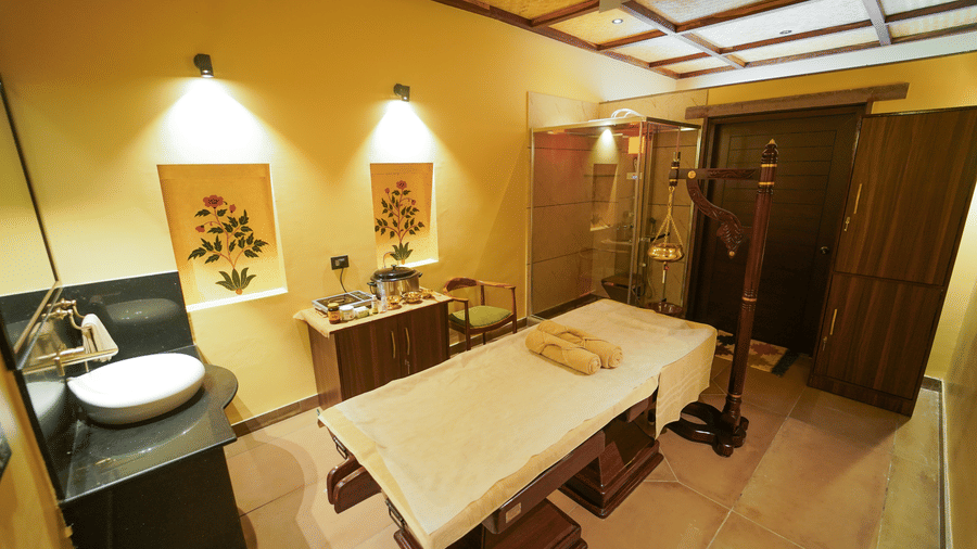 A spa room showing a massage bed alongside a small vanity unit at Aamaghati Wildlife Resort.