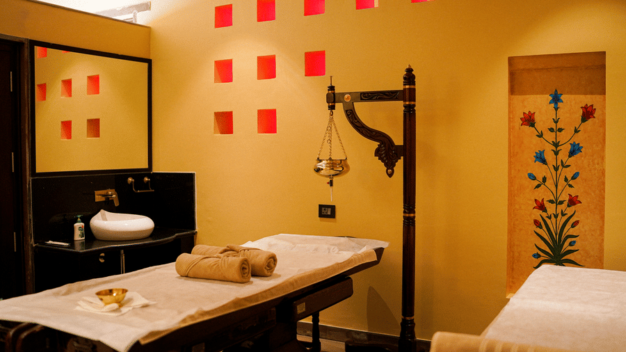 A well-appointed spa treatment room with warm lighting and a mirror at Aamaghati Wildlife Resort.