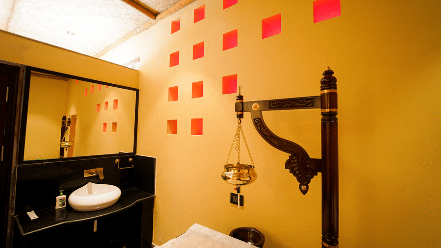 A vanity area with a basin, mirror, and decorative elements at Aamaghati Wildlife Resort.