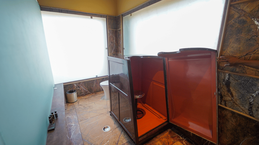 A bathroom area featuring a modern bathtub and wooden panels at Aamaghati Wildlife Resort.