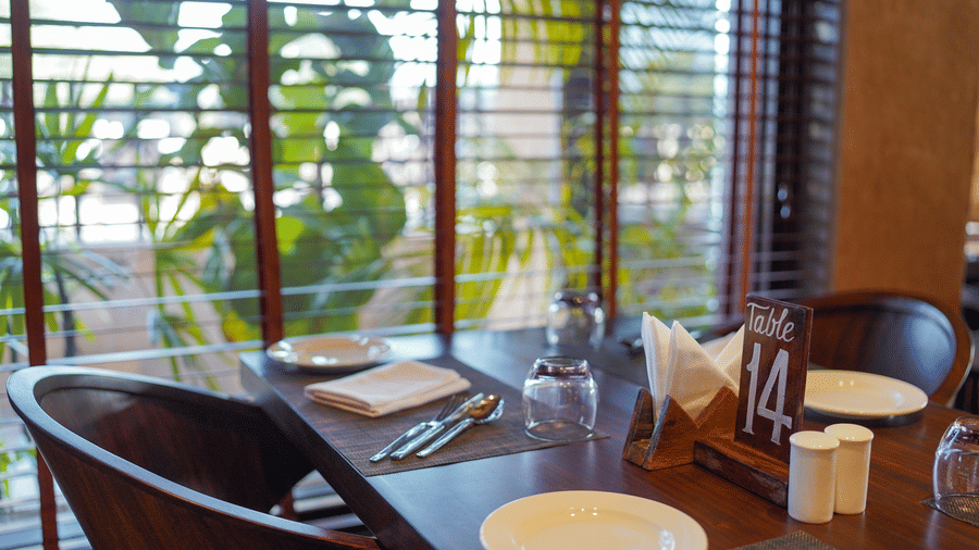 A dining table with a view of greenery through the window at Aamaghati Wildlife Resort.