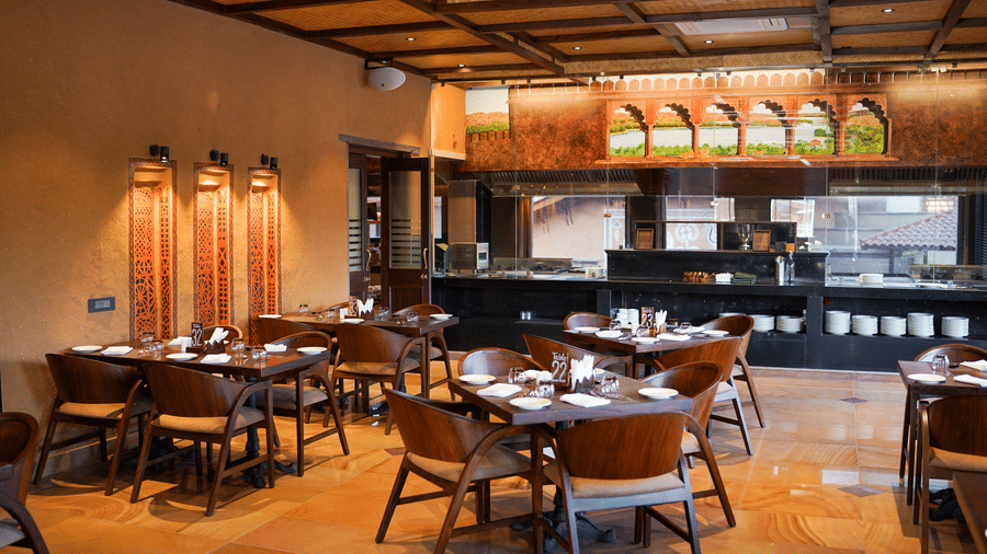 The restaurant interior featuring a long bar counter and dining tables at Aamaghati Wildlife Resort.