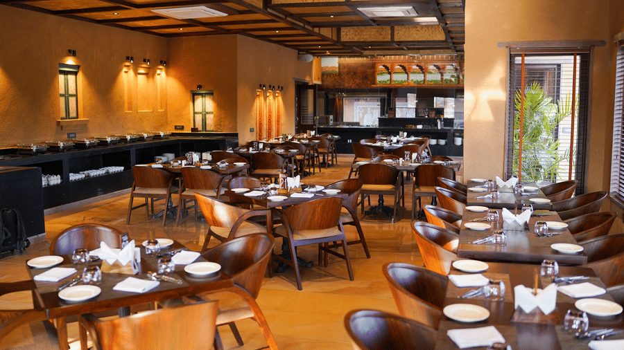 A spacious dining hall with numerous tables and chairs, ready for guests, at Aamaghati Wildlife Resort.
