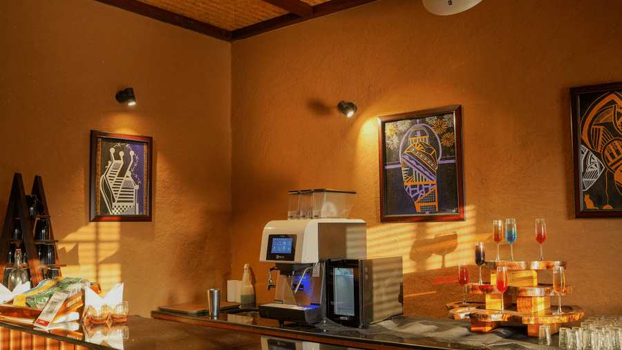A well-stocked bar or beverage counter with colourful bottles and equipment at Aamaghati Wildlife Resort.