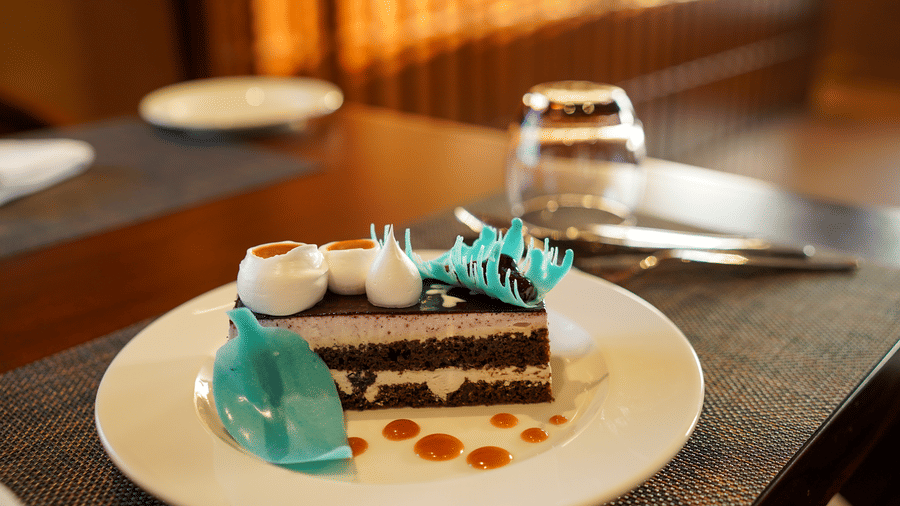 A slice of chocolate cake with blue and white decorations on a plate at Aamaghati Wildlife Resort.