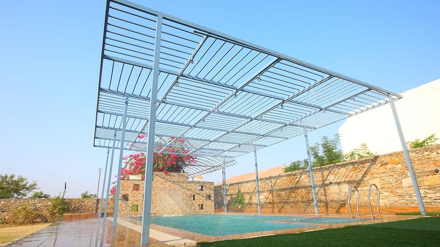 Open terrace swimming pool at Aanandam Resort & Spa, featuring Bougainvillea plants in the background and a serene view of the clear sky