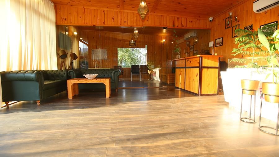 Reception area at Aanandam Resort & Spa featuring a large cozy sofa in the corner and a help desk on the opposite side