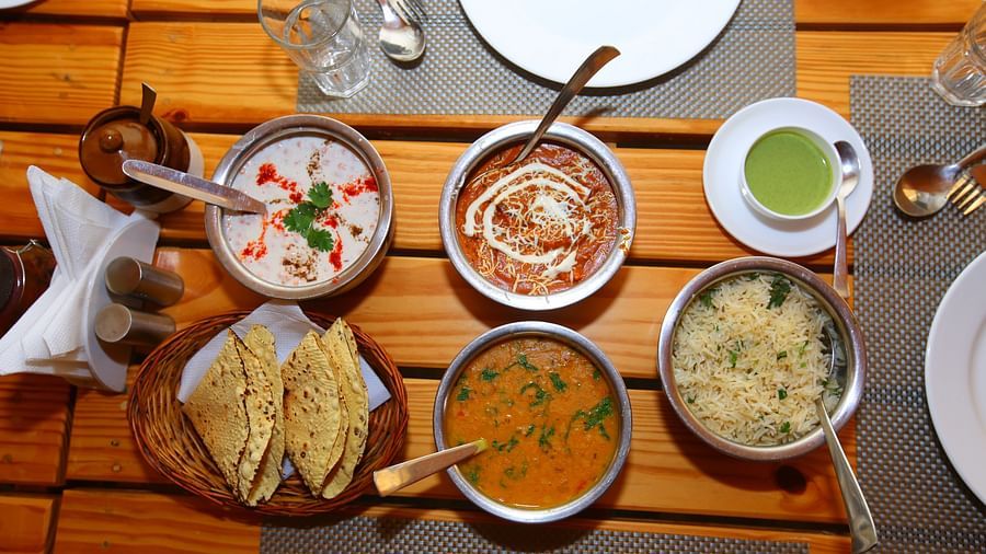 Image of Indian cuisine neatly arranged on the table with a tissue holder beside at Aanandam Resort & Spa
