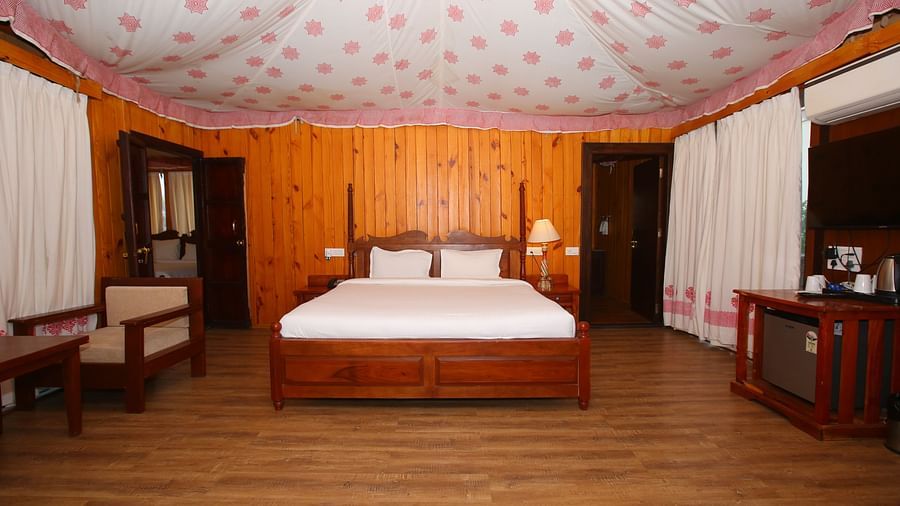Spacious Luxury Wooden Tent with a king-sized bed and a corner cupboard at Aanandam Resort & Spa