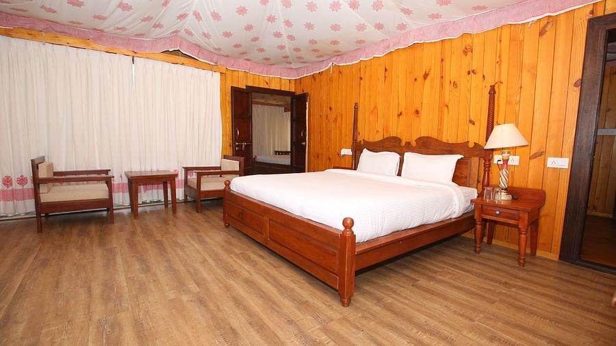 Luxury Wooden Tent featuring a king-sized bed, comfortable chairs, and stools at Aanandam Resort & Spa