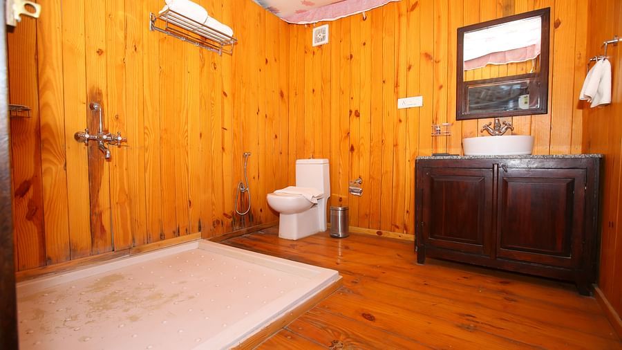 Luxury Wooden Tent washroom with a sleek sink, a separate bathing area, and elegant wooden flooring at Aanandam Resort & Spa
